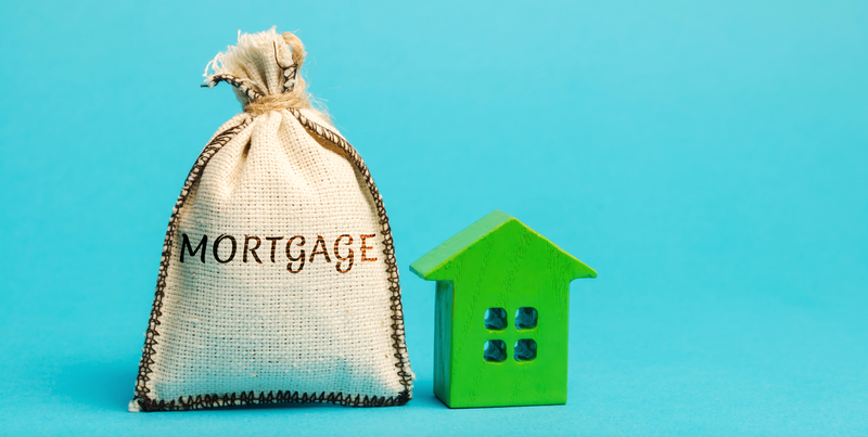 bag of money labelled as mortgage next to a little green house